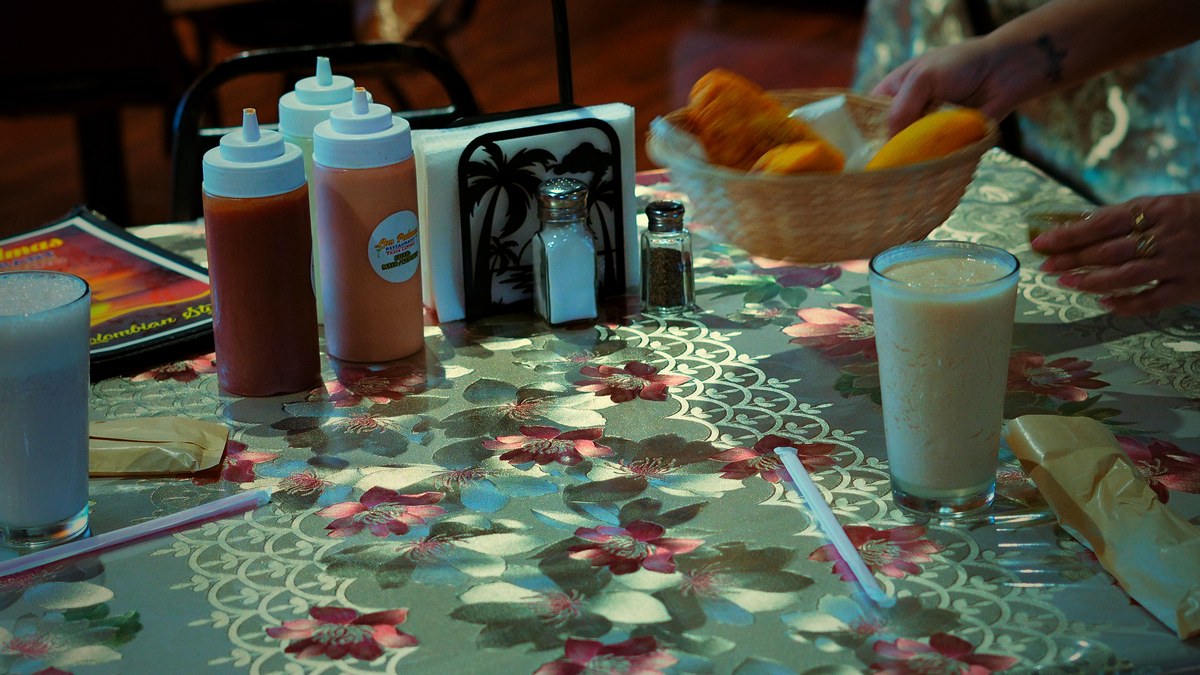 Una mesa con jugos, salsas y una canasta de empanadas.